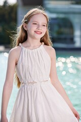 Smiling girl in white dress by the water.