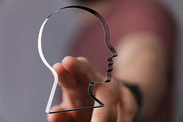 Abstract concept image: finger pointing at a glass head profile.  Ideal for psychology, AI, or identity.
