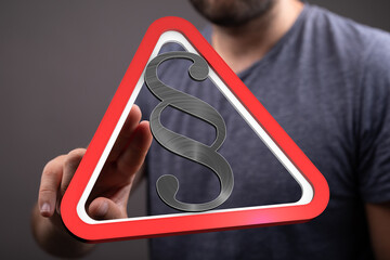 Stock photo of a hand interacting with a digital warning sign featuring a paragraph symbol,...