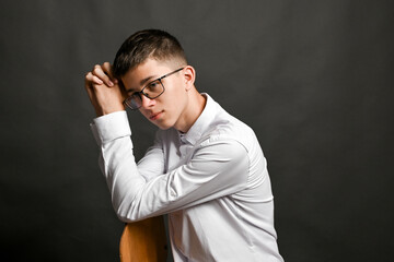 man leans on his folded arms with tense face, classic pose of deep thought or reverie. demonstrates excessive thinking. gesture indicating mental overload. guy with glasses on gray background