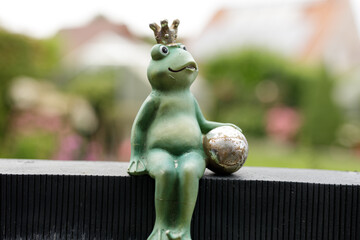 Charming garden figurine of a frog wearing a crown, holding a ball. Perfect for whimsical decor.
