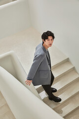 Young man in stylish outfit on modern staircase.