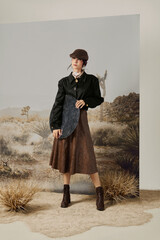 Woman in black outfit with a curved object in desert scenery.