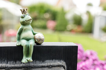 Charming garden decoration: a cute frog prince figurine holding a ball, perfect for outdoor spaces.