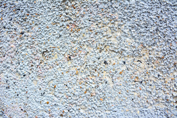 Small concrete grain texture. Textured concrete wall displays aggregate stones under natural light during the day in urban environment