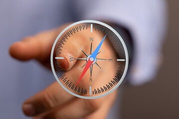Close-up of a hand interacting with a digital compass, symbolizing direction and guidance.