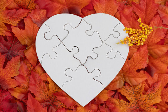 Blank puzzle heart with fall leaves for autumn season themes