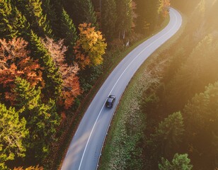 A single car on scenic curved road beautifully winds through a colorful autumn forest