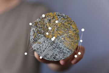 Abstract image of a person holding a digital globe showing network connections and city map. ...
