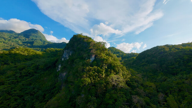 Mountain landscape with clouds. Aerial view of mountain range and peaks. Aerial view of mountains covered with green jungle and mountain peaks with rocky areas. - Powered by Adobe