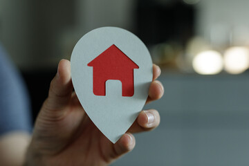 High-quality image of a hand holding a house-shaped location marker. Perfect for real estate,...