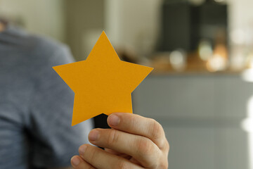 High-quality image of a hand holding a golden star, representing achievement, success, or...