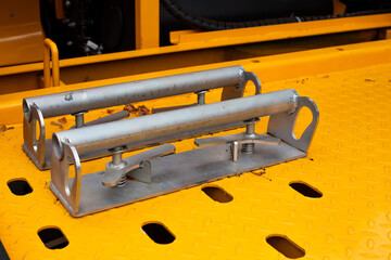 Close-up of wheel chocks on yellow tow truck platform, used to secure a car during towing. Metal...