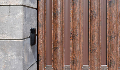 Gate pillar with black photocell sensor near picket fence