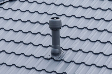 Plastic roof vent pipe on gray metal tile roofing © Sergey