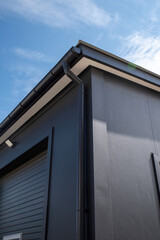 Plastic rain gutter with downspout on warehouse