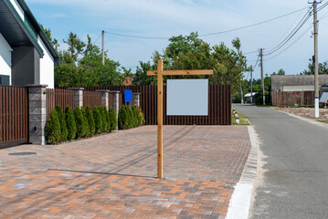Wooden post with hanging blank sign on paved street