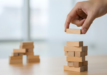 Building a business structure with wooden blocks. A hand carefully adds another level to a block tower, symbolizing strategic growth, project development, and building a strong foundation with precisi