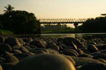 Fototapeta premium Pebbled Riverbank Under Soft Sunset Light