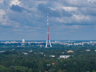 The Riga Radio and TV Tower stands tall with its red and white design, surrounded by greenery,...