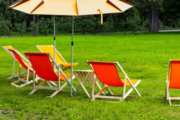 camping chairs and umbrella in a summer park. outdoor furniture for relaxation. a place to relax in...