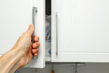 a man's hand opens a kitchen cabinet door. man opens closet, close-up