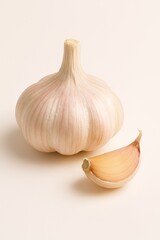 Fresh garlic bulb and a single clove on a clean, light background for cooking.
