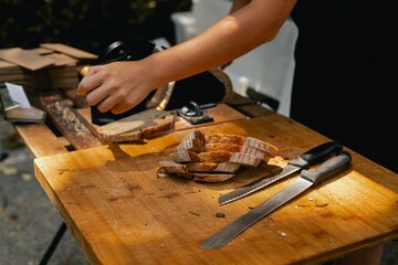 Hand-slicing craft bread on a table in a local Portuguese bakery. The healthy eating and traditional bakery concept. Close up. Part of the series