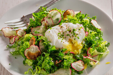 mixed green and radish salad topped with a poached egg