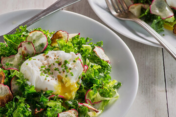 mixed green and radish salad topped with a poached egg