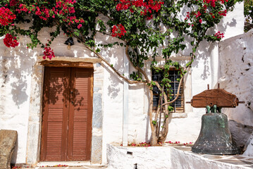 Historic whitewashed building with red flowers in Naxos, Greece