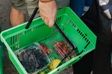 Close up of hand with a vegetables and greens in shopping basket on the local Farmers market....