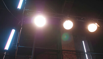 Stage lighting rig with spotlights and fluorescent tubes illuminating a dark space, creating a bright and dramatic effect.
