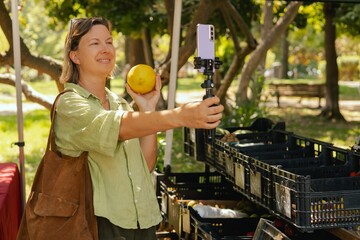 Middle-aged woman blogger filming on the farm market. Mature Female Customer Shopping At Farmers...