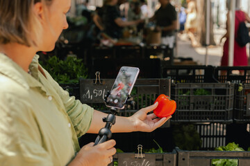 Middle-aged woman blogger filming on the farm market. Mature Female Customer Shopping At Farmers...