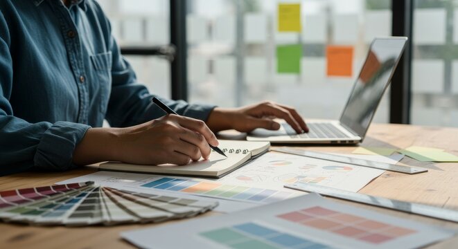 Creative Designer Writing and Researching Color Schemes at a Bright Workspace Desk