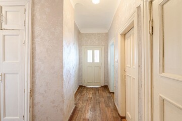 hallway with textured walls, white doors, and wood-look flooring. The hall leads to a door with windows