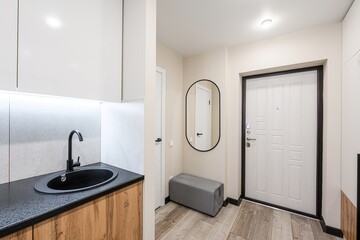 Bright hallway with a sink, oval mirror, and bench. The color palette is neutral with wood accents