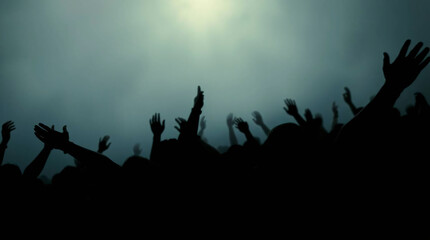 Silhouettes of a crowd with raised hands against a cloudy sky, creating a dramatic atmosphere.