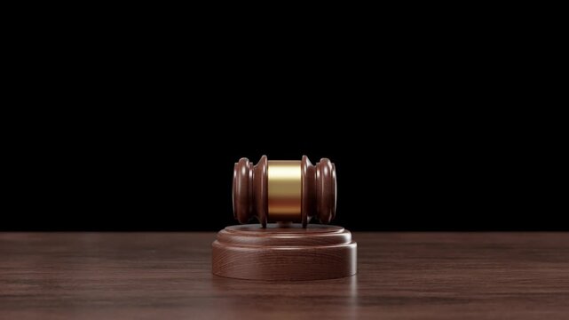 A solemn wooden judge's gavel on a dark desk is highlighted in this image, suitable for 3d render or keying into legal themed videos