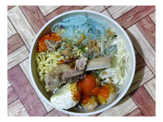 Bakso. A bowl of rib meatballs with yellow noodles, blue vermicelli, shredded cabbage, fried onions...