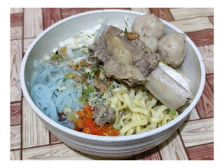 Bakso. A bowl of rib meatballs with yellow noodles, blue vermicelli, shredded cabbage, fried onions...
