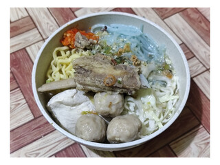 Bakso. A bowl of rib meatballs with yellow noodles, blue vermicelli, shredded cabbage, fried onions...