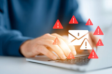 Hands typing on a laptop with warning icons and email symbol, representing phishing attack, spam mail, data breach risk, and cybersecurity threats in digital communication.