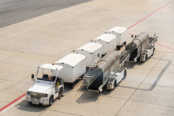 This is an airport baggage and cargo tractor pulling a train of luggage carts and container dollies. © gracethang