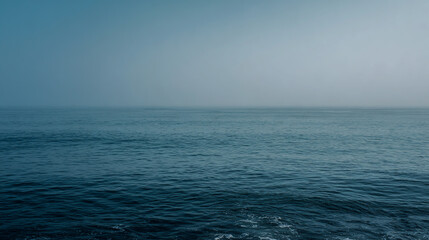 Misty ocean horizon with blue and gray water under a calm sky, tranquil seascape, soft atmospheric lighting, high-resolution.