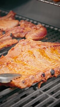 Close-up of raw marinated pork ribs placed on a barbecue grill, ready for cooking over hot charcoal.