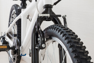 New white bicycle for child on light gray background. Closeup. Front view.