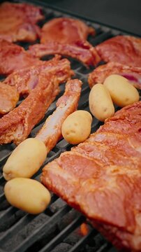Close-up of raw marinated pork ribs placed on a barbecue grill, ready for cooking over hot charcoal.