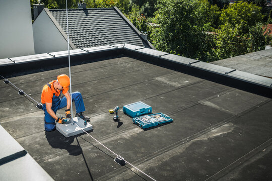 Technician Installing Lightning Protection System on Rooftop in a Residential Area During Daytime